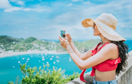 Foto de Chica viajera fotografiando una bahía desde un punto de vista. Mujer turista feliz en un sombrero fotografiando un punto de vista, Viajes y turismo concepto de promoción - Imagen libre de derechos