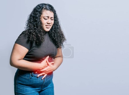 Foto de Mujer con dolor abdominal aislado. Mujer joven sufriendo dolor de estómago. Persona con dolor de estómago aislado - Imagen libre de derechos