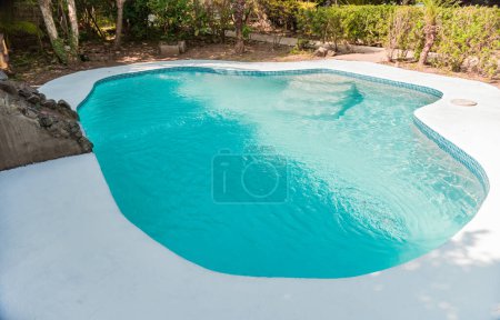 Téléchargez les photos : Conception de piscine pour la maison. Accueil piscine concept d'entretien. Piscine faite maison dans un jardin, piscine d'eau cristalline entourée d'un jardin - en image libre de droit