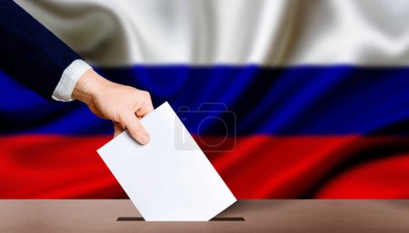 Poignée tenant le bulletin de vote dans l'urne avec drapeau russe en arrière-plan. Elections présidentielles de la Fédération de Russie