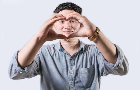 Handsome young man making heart shape with hands isolated. Smiling latin man making heart shape with hands