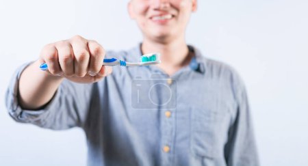 Lächelnde Person zeigt Zahnbürste mit isolierter Zahnpasta. Unbekannter hält Bürste mit Zahnpasta isoliert