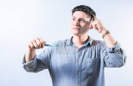 Pensive man holding toothbrush isolated. Thoughtful person holding toothbrush and looking up isolated