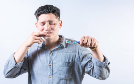 Persona con gingivitis que mantiene aislado el cepillo de dientes. Hombre sufriendo de dolor de encías sosteniendo el cepillo de dientes. Gente sosteniendo cepillo de dientes con problema de encías