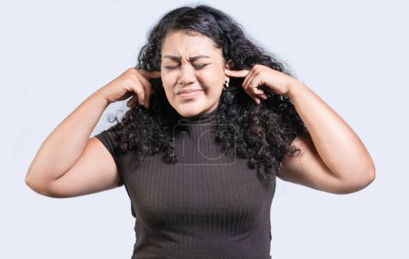 Frustrierte junge Frau, die ihre Ohren verdeckt und etwas Isoliertes ignoriert. Unzufriedenes Mädchen mit Brille, die ihre Ohren verdeckt