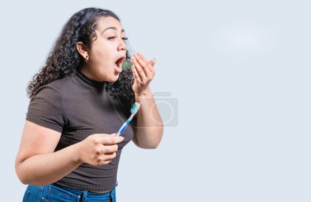 Photo for Young woman holding brush with bad breath isolated. Person with brush and bad breath isolated, Person with halitosis - Royalty Free Image