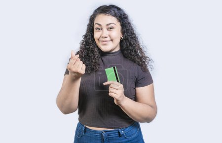 Muchacha atractiva sosteniendo tarjeta de crédito haciendo gesto de dinero con los dedos aislados, mirando a la cámara