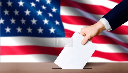 Hand hält Stimmzettel in Wahlurne, im Hintergrund die Flagge der USA. Konzept für Präsidentschaftswahlen in den USA