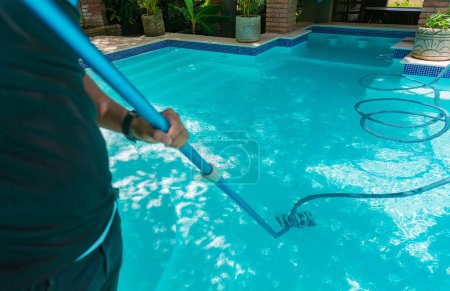Man cleaning swimming pool with suction hose. Person cleaning a swimming pool with a vacuum hose