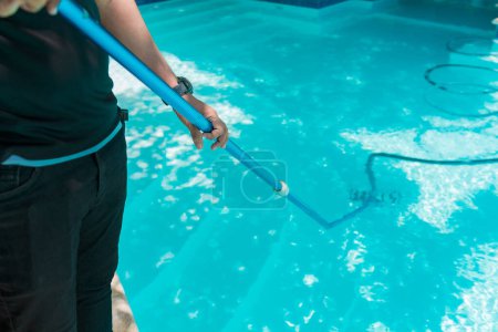 Persona que limpia una piscina con una manguera de vacío. Hombre limpieza piscina con manguera de succión