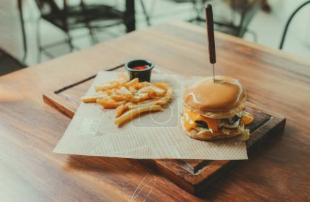 Hamburger appétissant avec frites servi sur une table en bois. Hamburger traditionnel avec frites servi sur une table de restaurant