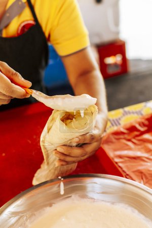 Hände, die ein nicaraguanisches Quesillo machen. Großaufnahme von Händen, die ein traditionelles Quesillo mit eingelegten Zwiebeln zubereiten. Zubereitung von nicaraguanischem Quesillo, traditionellem zentralamerikanischem Quesillo