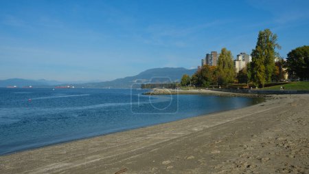 Téléchargez les photos : Public City Beach par une journée ensoleillée. Calme l'eau de mer. Bâtiments sur la côte. - en image libre de droit
