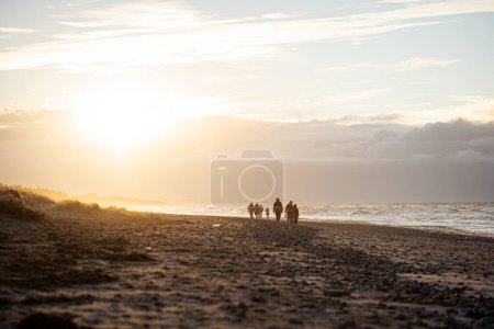 Photo for Tisvildeleje, Denmark - January 21, 2022: People walking at Tisvildeleje beach during sunset - Royalty Free Image