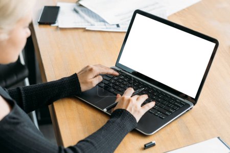 Foto de Trabajo en línea. Una maqueta de computadora. Búsqueda en red. Mujer irreconocible escribiendo portátil pantalla en blanco escritorio de estar sala de luz interior. - Imagen libre de derechos
