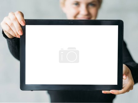Foto de Una maqueta de computadora. Fondo publicitario. Tecnología digital. Mujer irreconocible sosteniendo tableta con pantalla en blanco. - Imagen libre de derechos