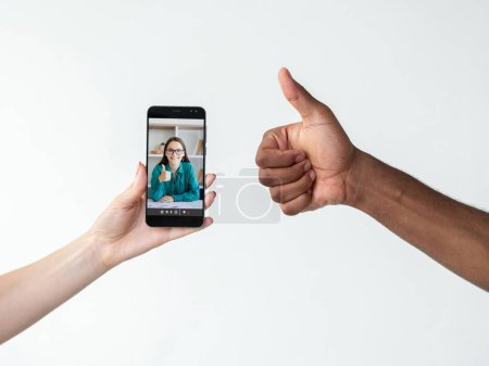 Photo for Internet feedback. Online deal. Video conference. Diverse hands showing agreement thumb up with satisfied business woman on phone screen isolated on white copy space. - Royalty Free Image