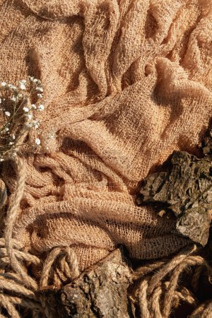 Foto de Rustic showcase. Product placement. Nature composition. Cracked brown wood bark pieces twisted rope dried flowers on beige crumpled sack cloth free space decorative background. - Imagen libre de derechos