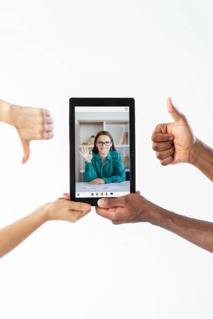 Téléchargez les photos : Online feedback. Video interview. Virtual meeting. Diverse hands showing thumb up down to business woman on tablet screen isolated on white copy space. - en image libre de droit