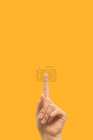Foto de Advertising gesture. Attention idea. Information announcement. Female hand finger pointing up at bright orange copy space commercial background. - Imagen libre de derechos