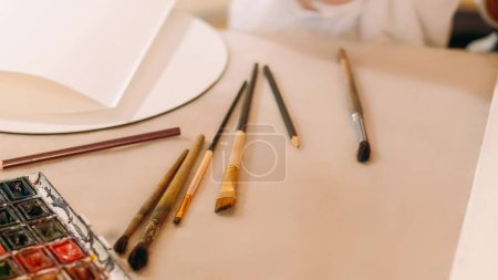 Foto de Artist workplace. Painting tools. Art supplies. Watercolor paint palette brush set pencil professional painter essentials at copy space. - Imagen libre de derechos