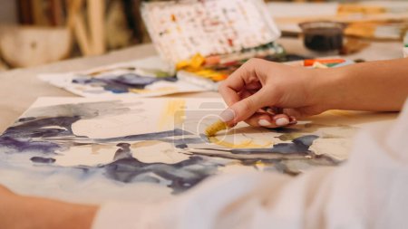 Foto de Painting art. Creative process. Talent imagination. Female artist hand creating yellow blue abstract artwork with wax crayon watercolor on canvas. - Imagen libre de derechos