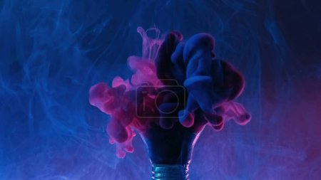 Téléchargez les photos : Color fume. Paint splash. Vapor cloud. Pink blue explosion smoke in broken light bulb in water on dark mist art abstract background. - en image libre de droit