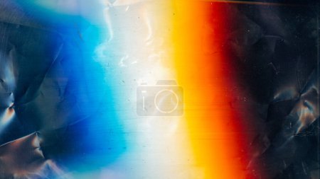 Foto de Distressed overlay. Dust scratches texture. Creased old film noise. Orange blue white rainbow color glow on dark wrinkled uneven abstract background. - Imagen libre de derechos