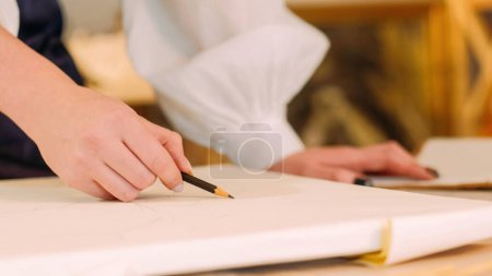 Photo for Artwork drawing. Painting art. Creative process. Closeup of female artist hand sketching line with pencil on white canvas at workplace with free space. - Royalty Free Image