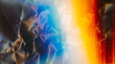 Foto de Distressed film texture. Light flare. Uneven aged surface. Orange blue white rainbow color glow dust scratches on dark wrinkled crumpled abstract background. - Imagen libre de derechos