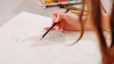 Téléchargez les photos : Sketching hobby. Painting art. Creative process. Closeup of female artist hand drawing lines with pencil on white canvas at workplace with free space. - en image libre de droit