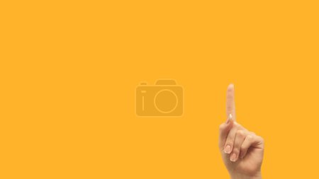 Foto de Attention gesture. Idea promotion. Information here. Female hand recommending something invisible finger pointing up at yellow empty space background. - Imagen libre de derechos