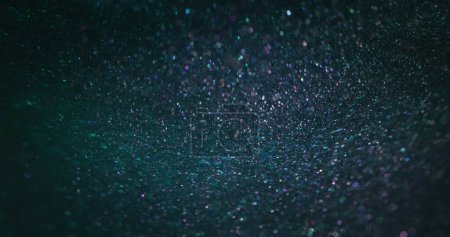Téléchargez les photos : Glitter background. Bokeh light texture. Nebula star dust. Defocused neon purple blue shiny round particles on dark abstract wallpaper with free space. - en image libre de droit