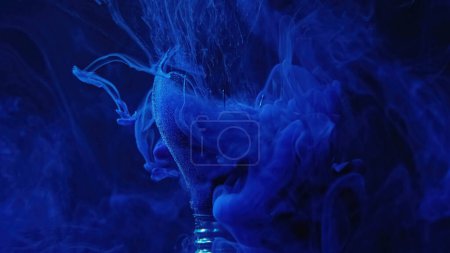 Foto de Broken lamp smog cloud. Ink water shot. Defocused blue color haze floating in crashed glass light bulb on dark abstract background. - Imagen libre de derechos