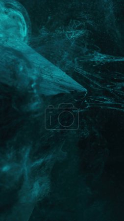 Foto de Ink splash abstract background. Mountain frost. Blur turquoise green color vapor floating texture over glass pyramid cube angle on dark. - Imagen libre de derechos
