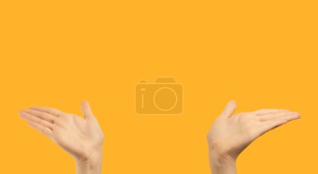 Foto de Advertising gesture. Special offer. Introduction presentation. Female hands showing something invisible with open palms on orange copy space commercial background. - Imagen libre de derechos