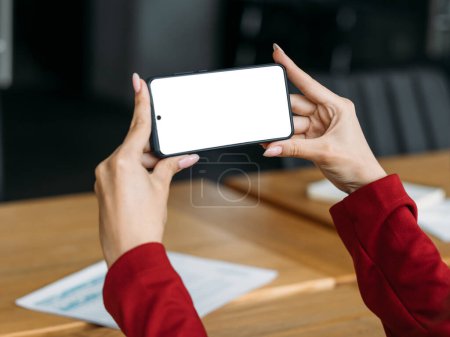 Photo for Digital mockup. Virtual meeting. Mobile technology. Unrecognizable woman holding smartphone with blank screen sitting light room interior. - Royalty Free Image