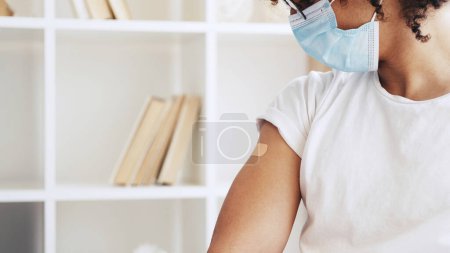 Photo for Virus vaccination. Flu immunization. Medical care. Unrecognizable male patient in face mask with adhesive bandage after jab on arm shoulder. - Royalty Free Image