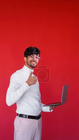 Photo for Digital business. Online work. Satisfied cheerful smart business man with laptop recommending computer program with thumb up on red empty space background. - Royalty Free Image