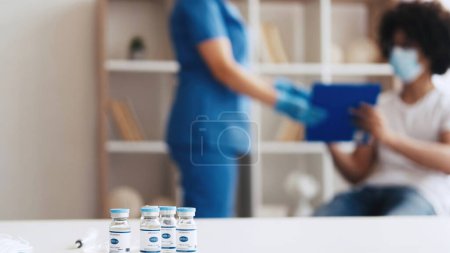 Photo for Covid-19 vaccination. Pandemic immunization. Coronavirus prevention. Unrecognizable male patient signing agreement form to nurse to get flu shot dose in clinic. - Royalty Free Image