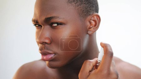 Photo for Aftershave spray. Skin care. Male grooming. Closeup portrait of confident man applying facial antiseptic anti irritation cosmetic product on clean face on light free space. - Royalty Free Image
