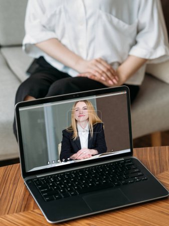 Photo for Online counseling. Web chat. Remote conference. Female professional expert on laptop screen working with woman on couch at home interior. - Royalty Free Image