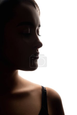 Photo for Female face. Beauty enhancement. Aesthetic cosmetology. Nose rhinoplasty. Closeup dark silhouette profile portrait of woman with closed eyes on white free space background. - Royalty Free Image