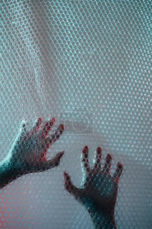 Photo for Nightmare horror. Emotional trap. Mental disorder. Defocused female hands clawing scratching transparent plastic bubble wrap textured wall free space background. - Royalty Free Image