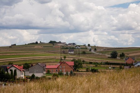 Photo for Countryside panorama. Rural scenery. Landscape view. Farmland houses on meadow hills with fields path on fluffy clouds daylight sky. - Royalty Free Image