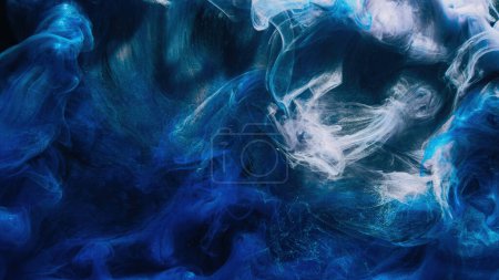 Paint water. Smoke texture. Acrylic ink splash. Blue color glowing shiny fog cloud on black abstract art background with free space.