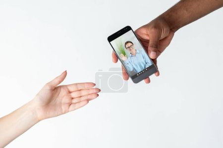 Photo for Video consulting. Online expert. Virtual interview. Diverse hands sharing phone with smart female specialist on screen isolated on white copy space. - Royalty Free Image