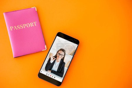 Photo for Passport service. Online expert. Digital immigration center. Satisfied business woman approving visa with okay gesture on phone screen on orange copy space background. - Royalty Free Image