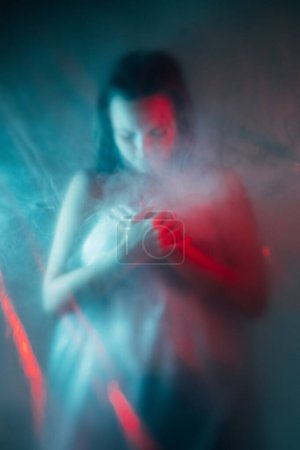 Photo for Air pollution. Toxic smog. Environment contamination. Climate disaster. Red blue color light defocused exhausted suffering woman silhouette in smoke cloud. - Royalty Free Image