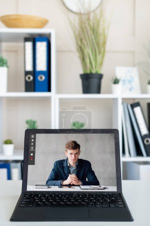 Photo for Video interview. Web chat. Online conference. Internet meeting. Dissatisfied business man on laptop screen at digital office interior. - Royalty Free Image